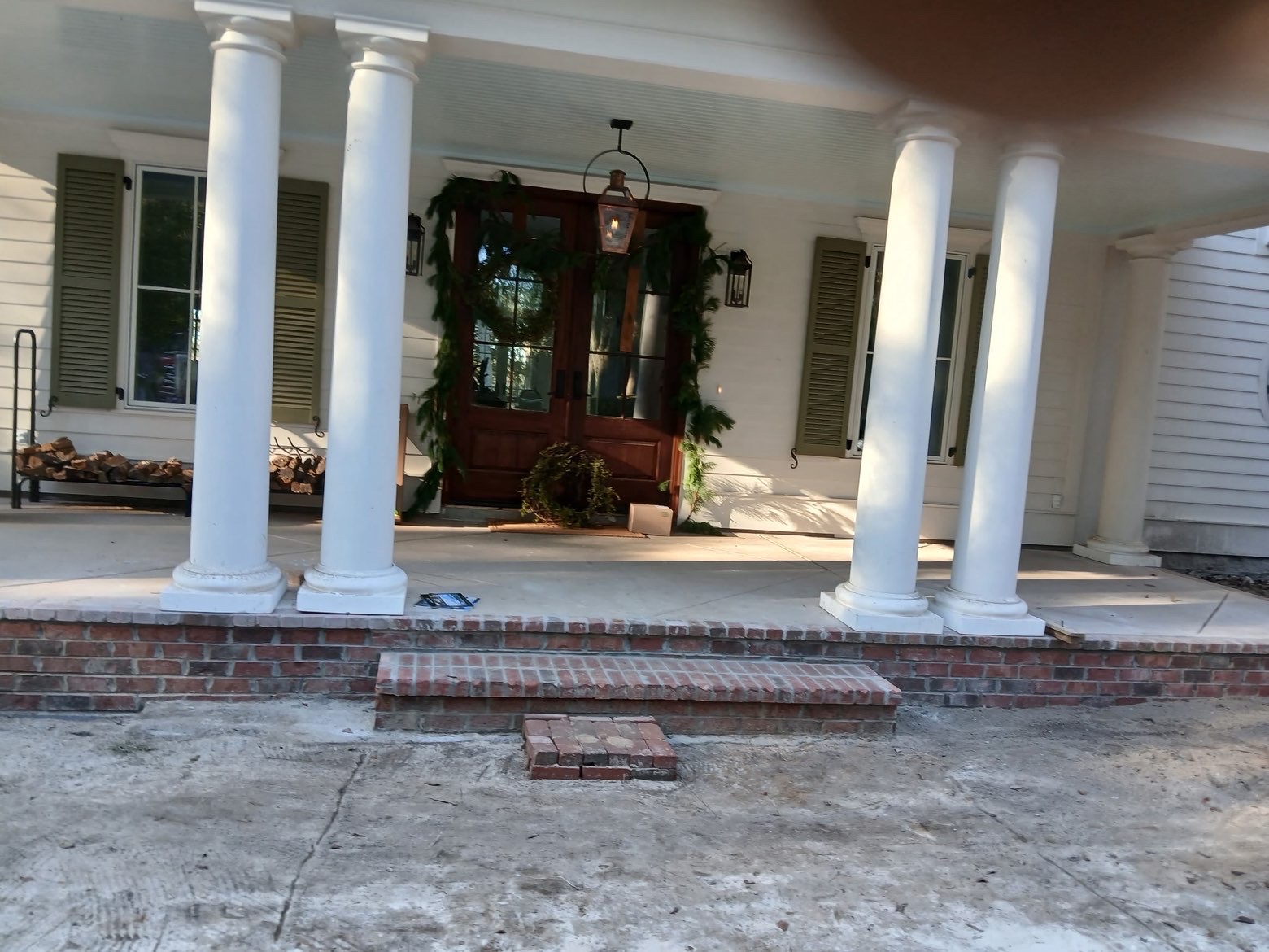 Finished front porch with white columns and brick base